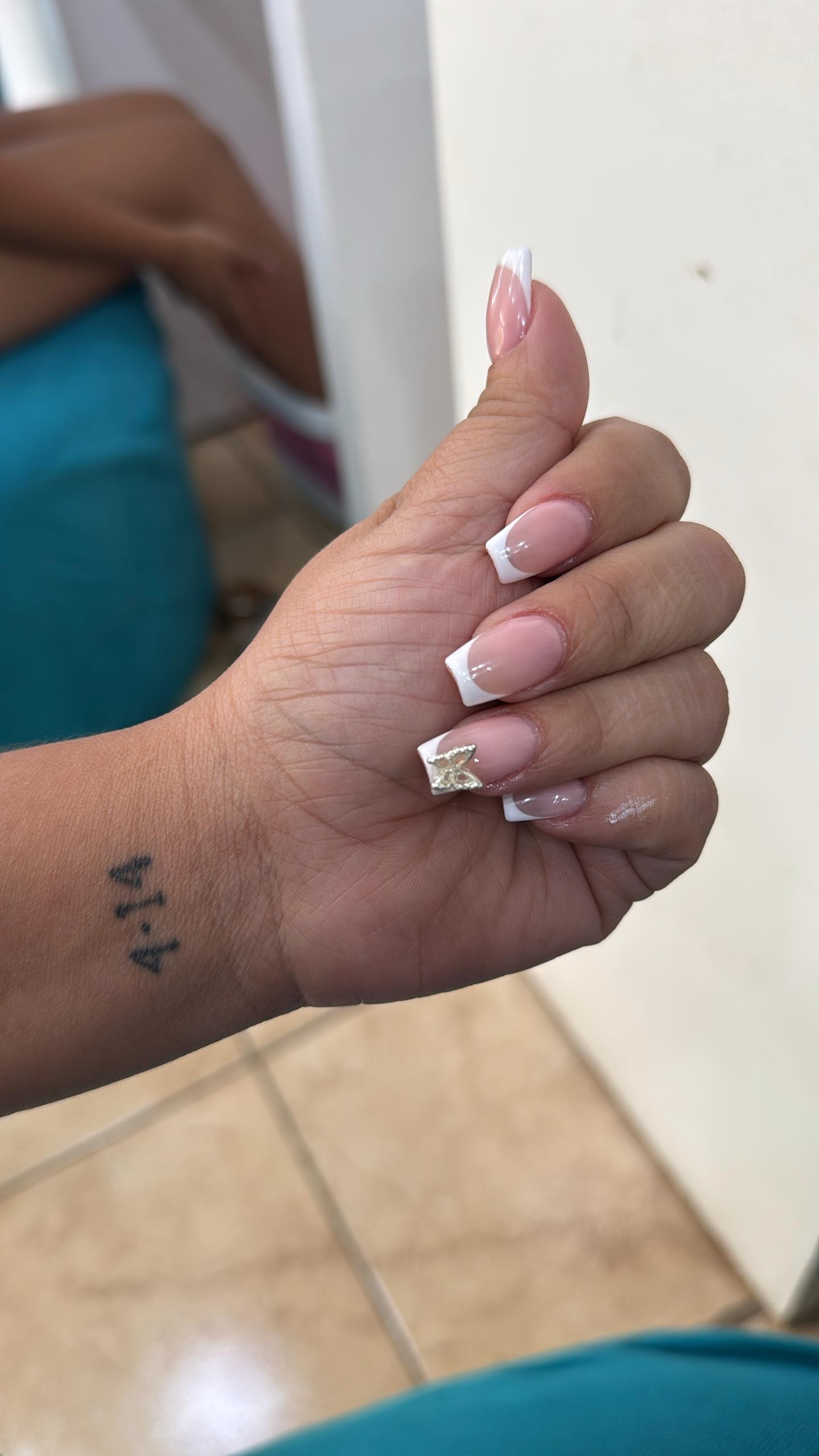 Soft pink French tip nails with a gold accent detail