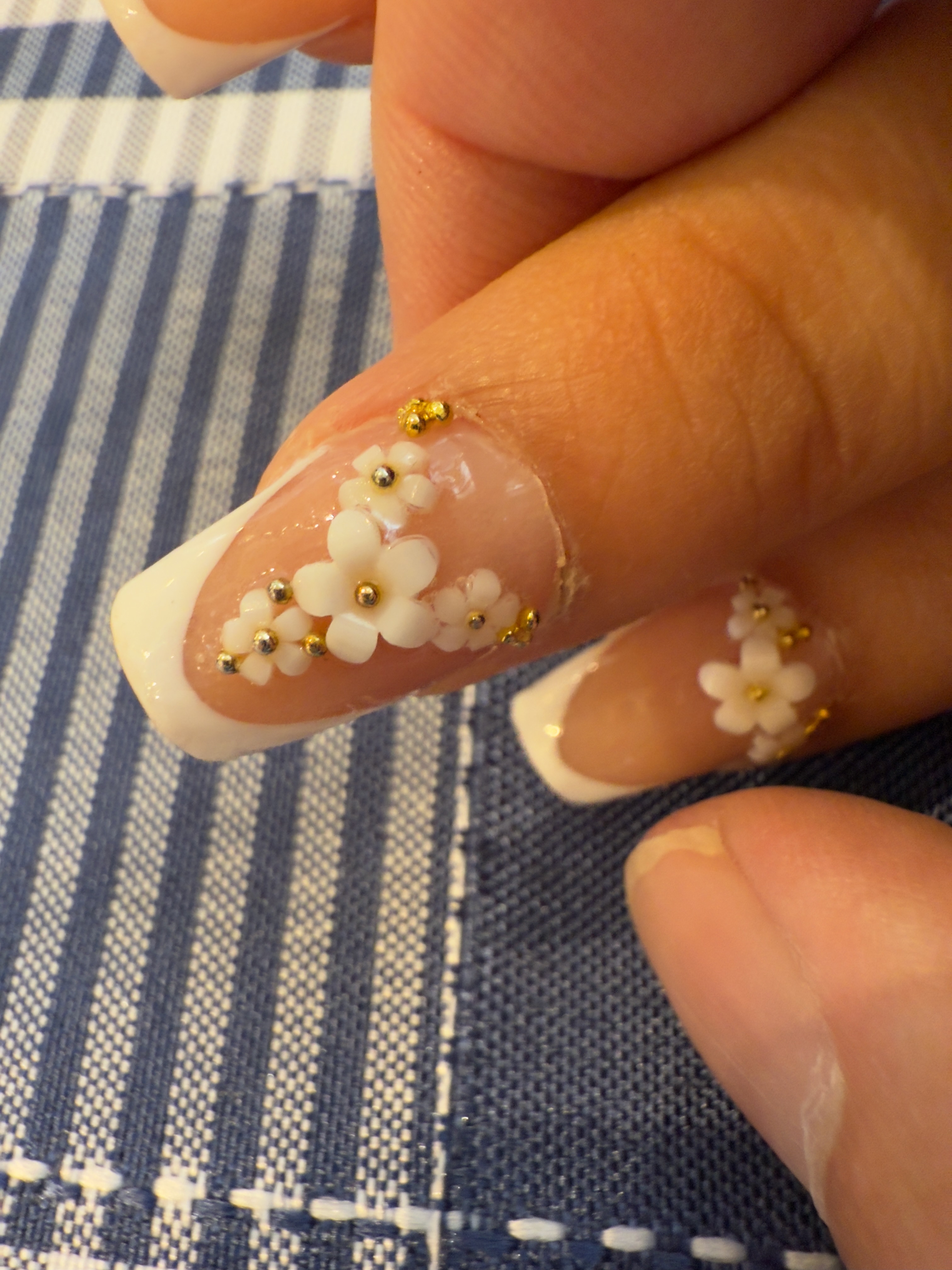 French tip nail with white floral accents and gold studs